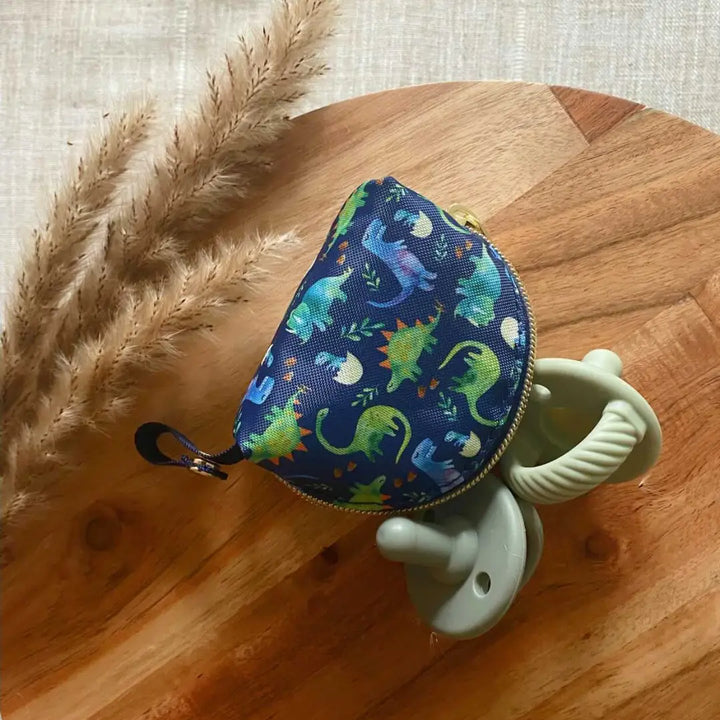 Itzy Ritzy Pacifier Pouch holding two pacifiers in the dino print