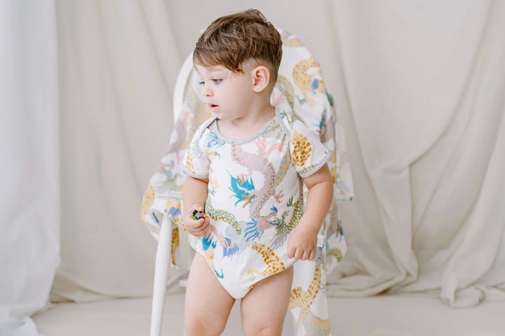 Lifestyle view of a child standing while wearing Short Sleeve Onesie (Bamboo) - Dragon Dance (Sizes 12 Months - 2T)