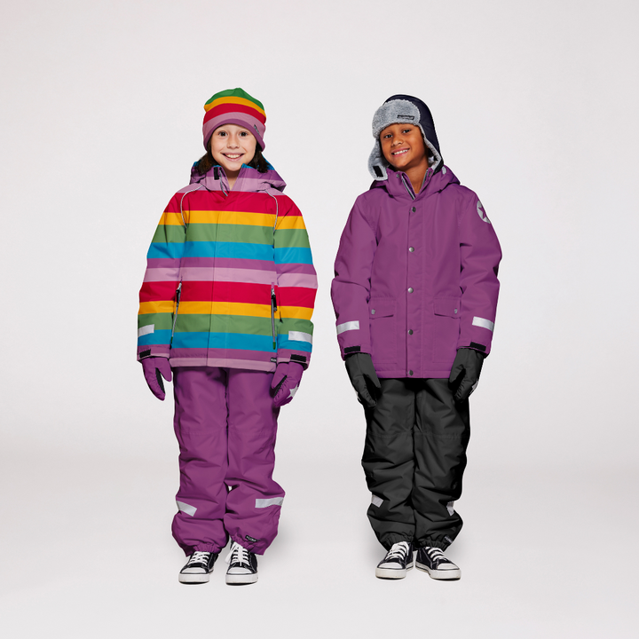 Two children wearing villervalla snow gear. The one on the left wearing a striped jacket with purple snowpants, and the one on the right wearing a pruple snow jacket with black snow pants. They are wearing coordinating acceesories on a white background