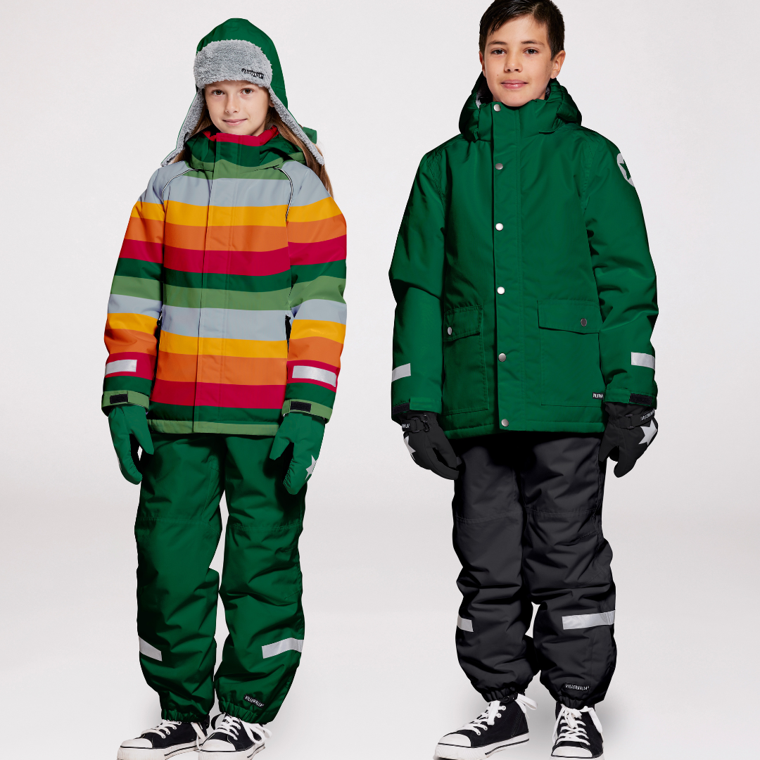 Two children on a white background where snow gear. The one on the left in a striped jacket with green snow pants, and the one on the right wearing a green jacket with black snow pant.s Both have coordinating accessoires. 