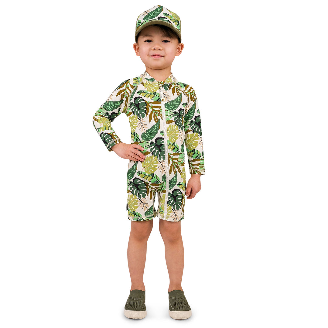 Child wearing Jan & Jul UV Jumpsuit | Green Tropical. The child is a size 3T and weighs 35lbs and is 40.5 inchs. The child is wearingcoordianting Green torpical accessories and has his hand on his hip facing us.