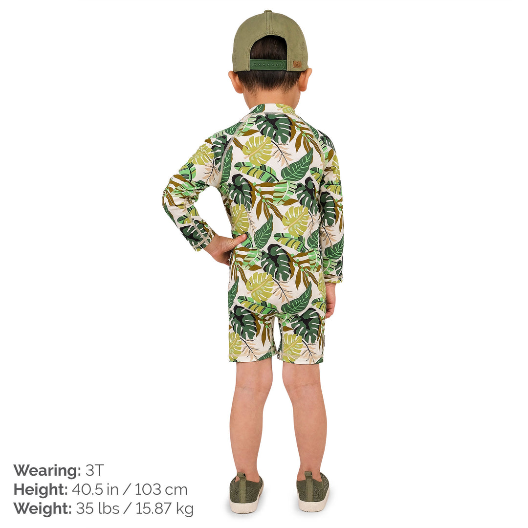 Child wearing Jan & Jul UV Jumpsuit | Green Tropical. The child is a size 3T and weighs 35lbs and is 40.5 inchs. The child is wearingcoordianting Green torpical accessories and has his hand on his hip and turned with his back in the image