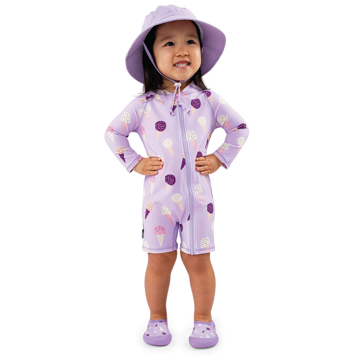 Child wearing the 18-24 month size Jan & Jul UV Jumpsuit | Lavendar Ice Cream who is 35.5 inches nad 31lbs, the child is also wearing matching water play shoes and standing facing us with a sunhat on