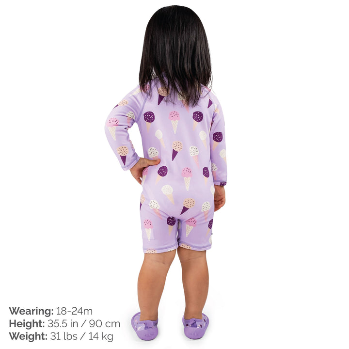 Child wearing the 18-24 month size Jan & Jul UV Jumpsuit | Lavendar Ice Cream who is 35.5 inches nad 31lbs, the child is also wearing matching water play shoes and standing with her back to us