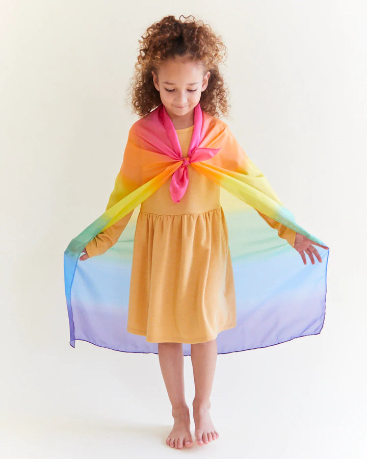 Child wearing rainbow silk as a cape