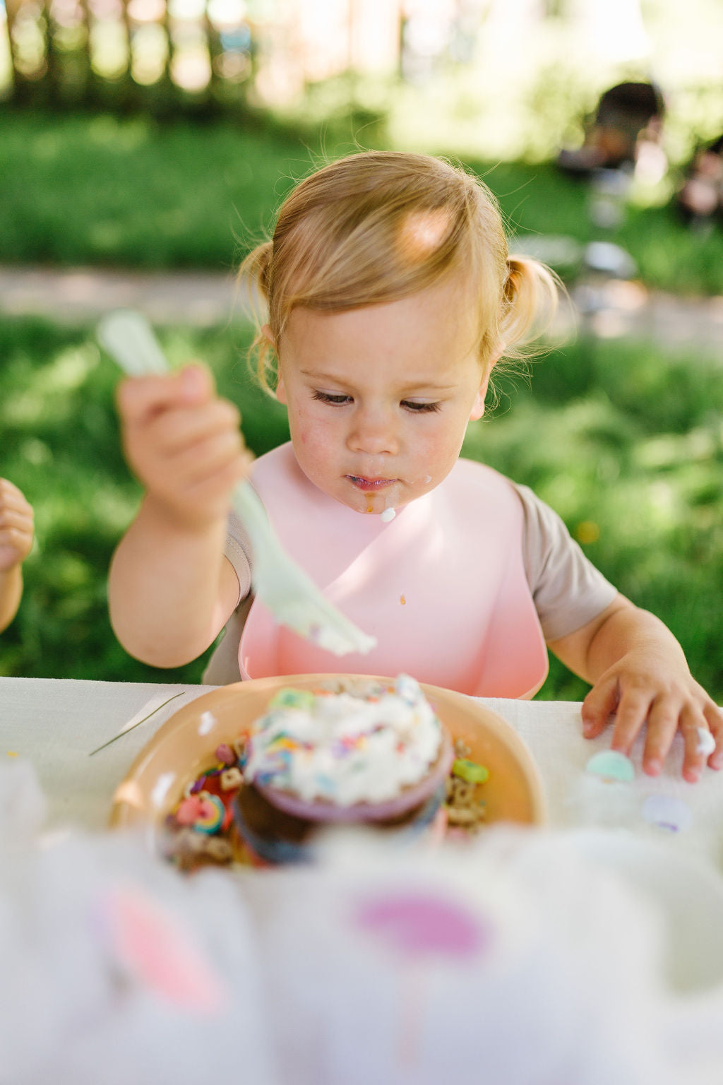 child eating a cupcake with a silicone bib for their first birthday Loulou Lollipop Silicone Bib